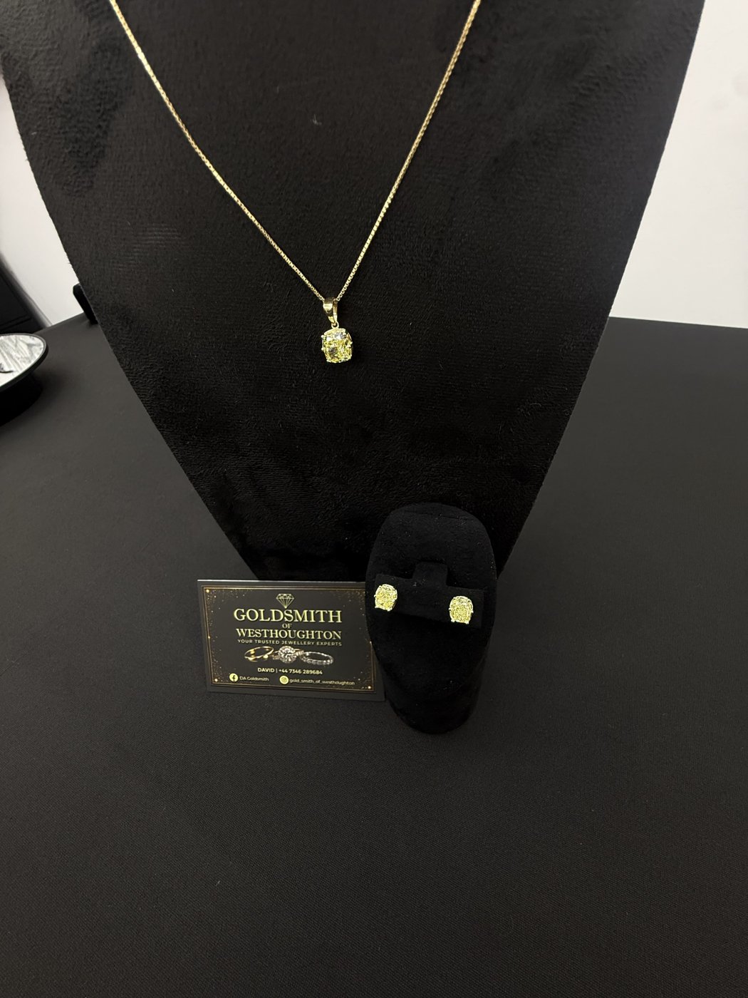 Pendant necklace and earrings on a black display