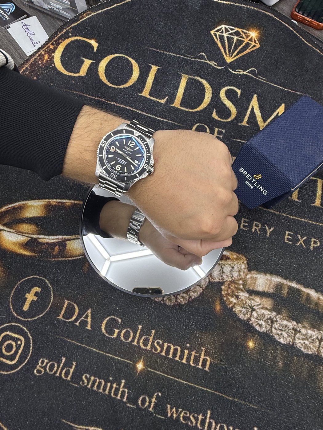 Watch worn on a wrist in front of DA Goldsmith artwork