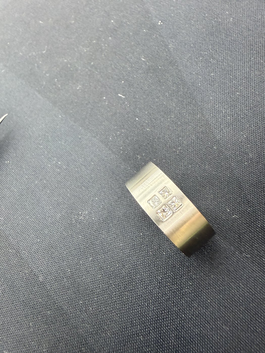 Engraved metal band resting on a grey surface