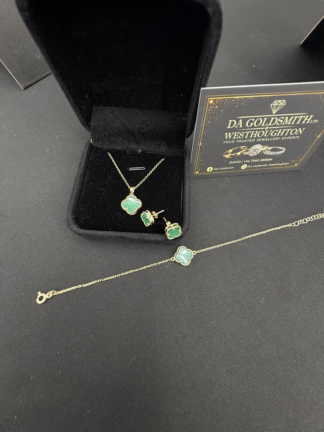 Green pendant, earrings and bracelet beside a black box