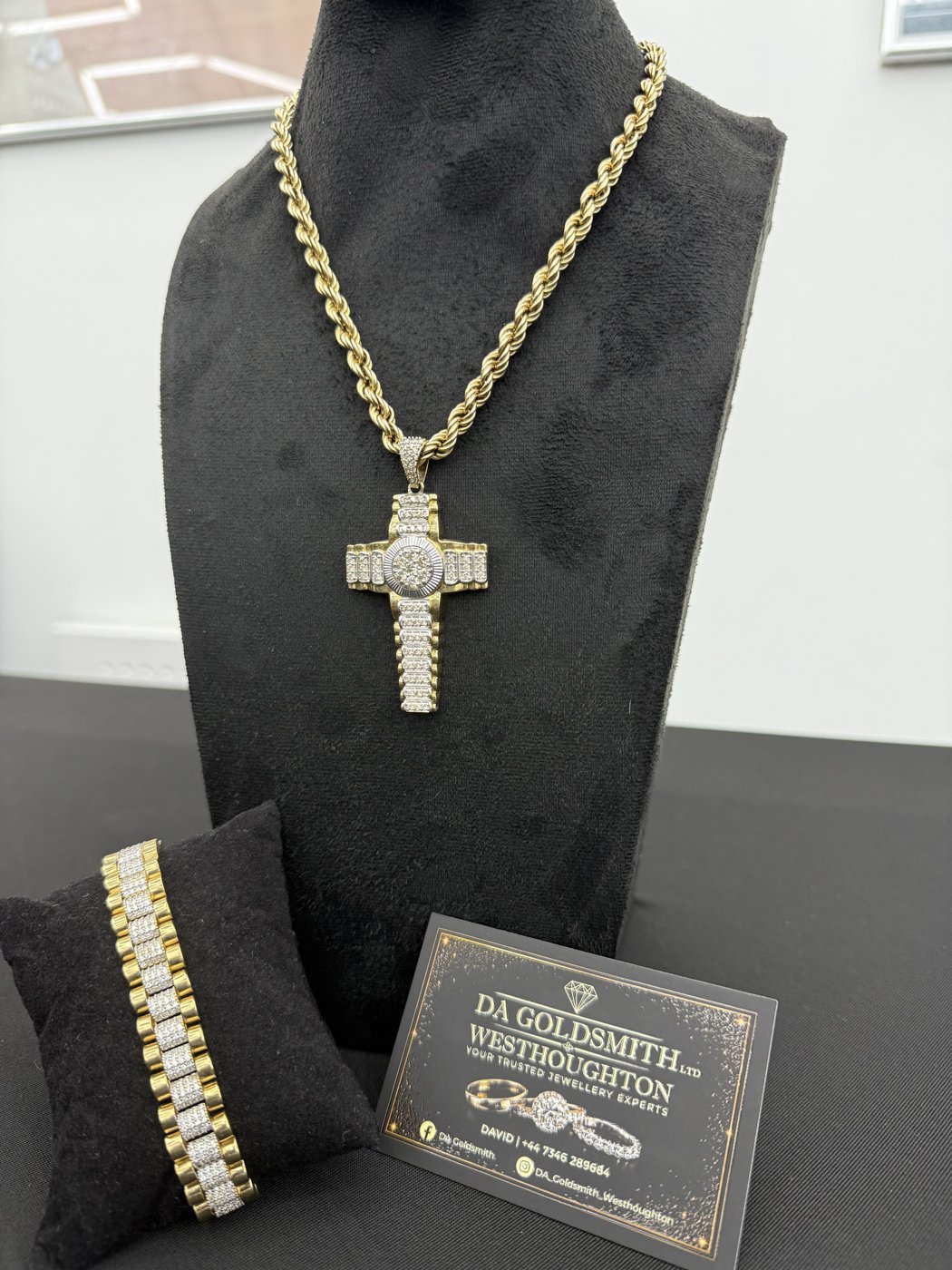 Cross pendant necklace and bracelet on black displays