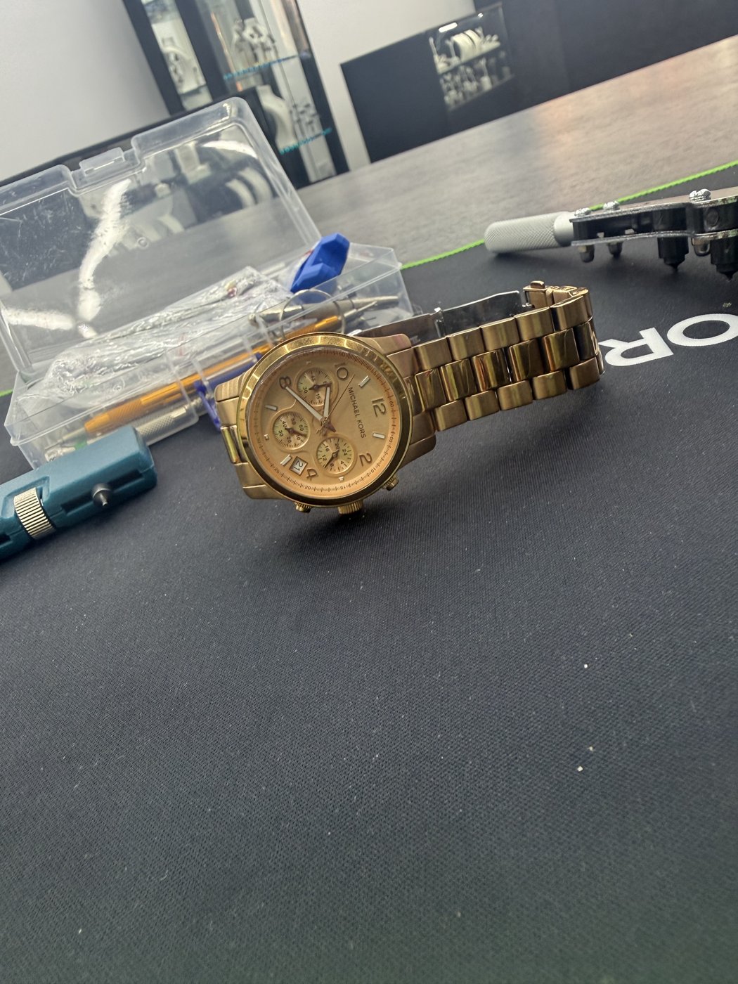 Watch resting on a counter with tools nearby